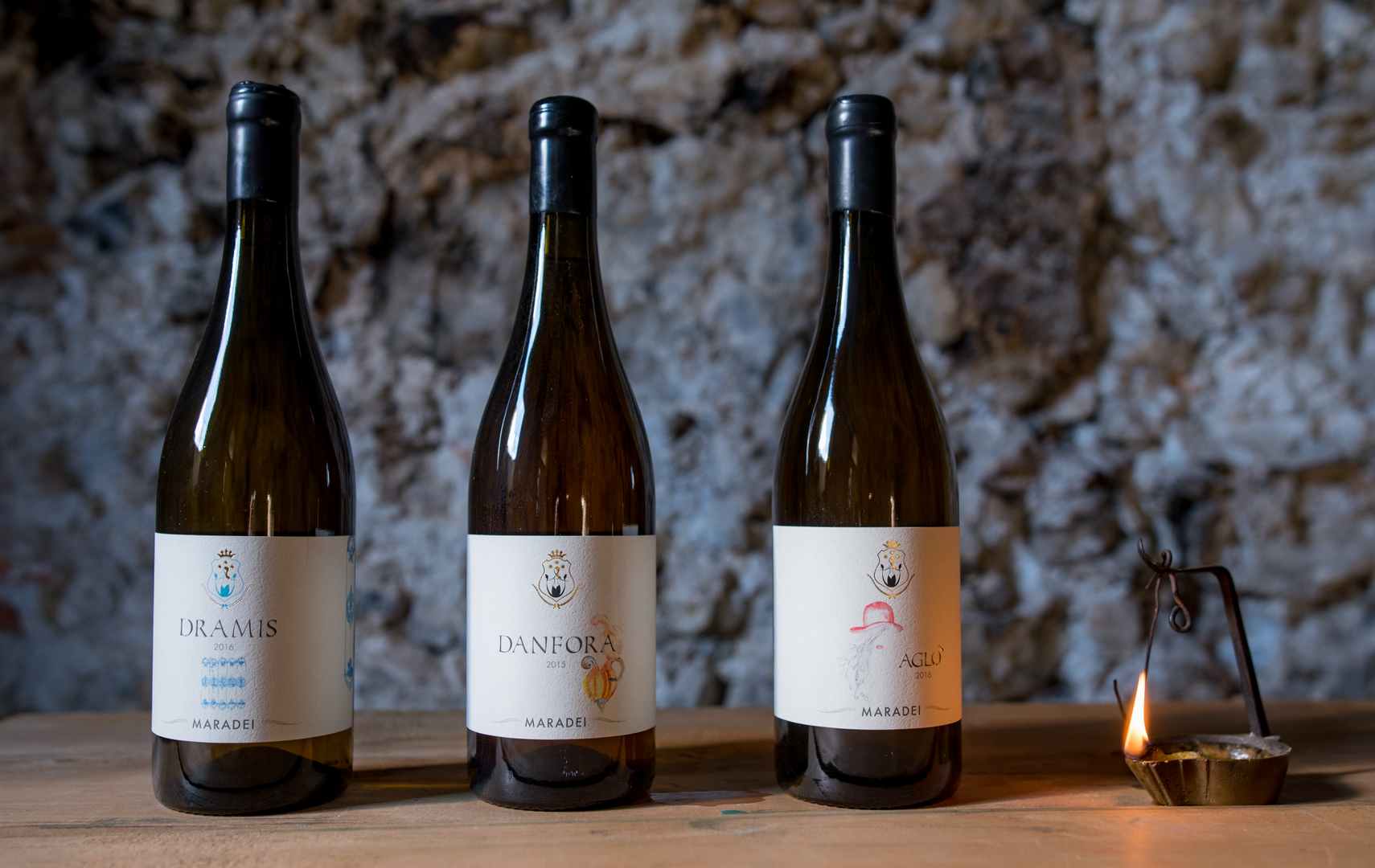 Tre bottiglie di vino bianco Tenuta di Ghizzano in cantina con candela